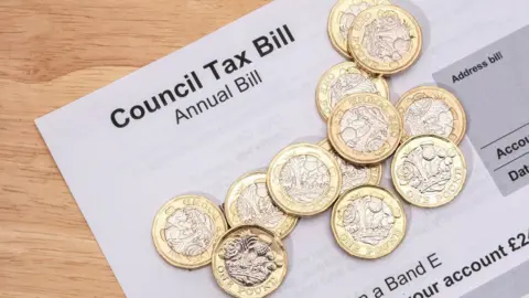 Getty Images coin piled on top of Scottish council tax bill