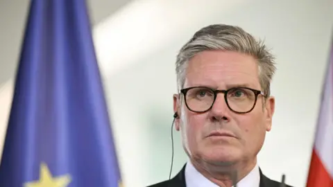 PA Media Sir Keir Starmer, frowning, with the European Union flag behind him